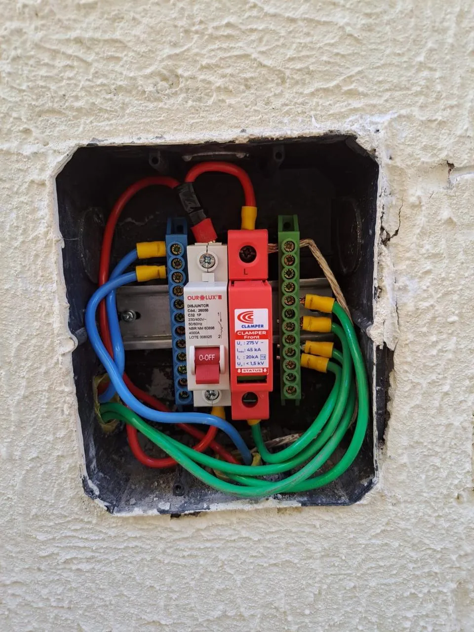 Quadro de proteção aberto com disjuntores, DPS e cabos identificados por cor